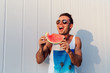 Joyful man laughing hard while eating a watermelon outdoors.