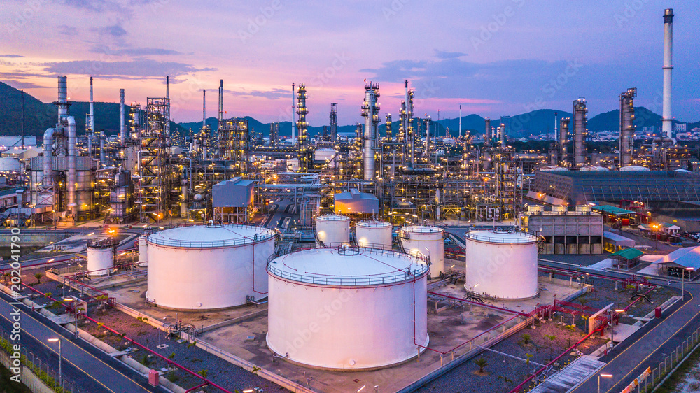 Aerial view oil and gas chemical tank with oil refinery plant background at twilight, business power and energy chemical barrel. - obrazy, fototapety, plakaty 