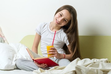 Wall Mural - Teenage girl reads book and holds orange juice.