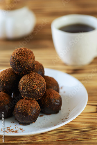 Fotografie, Obraz Chocolate petit fours on a wooden table with a cup of coffee