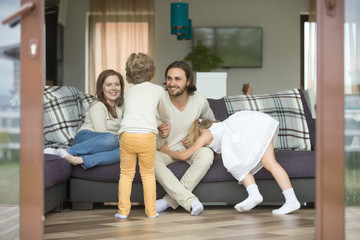 Wall Mural - Happy cheerful family playing at home on weekend, active kids having fun with parents relaxing on sofa in cozy living room, smiling mom and dad enjoying spending time with children son and daughter