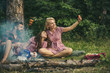 © Volodymyr - Blond girl taking selfie in forest. Smiling friends posing with sausages. Youngsters camping in woods