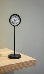 Wall Mural - Classic analog clock with metal stand on shelf