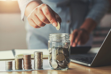 Poster - businesswoman hand puting coins in glass for saving money. concept finance and accounting