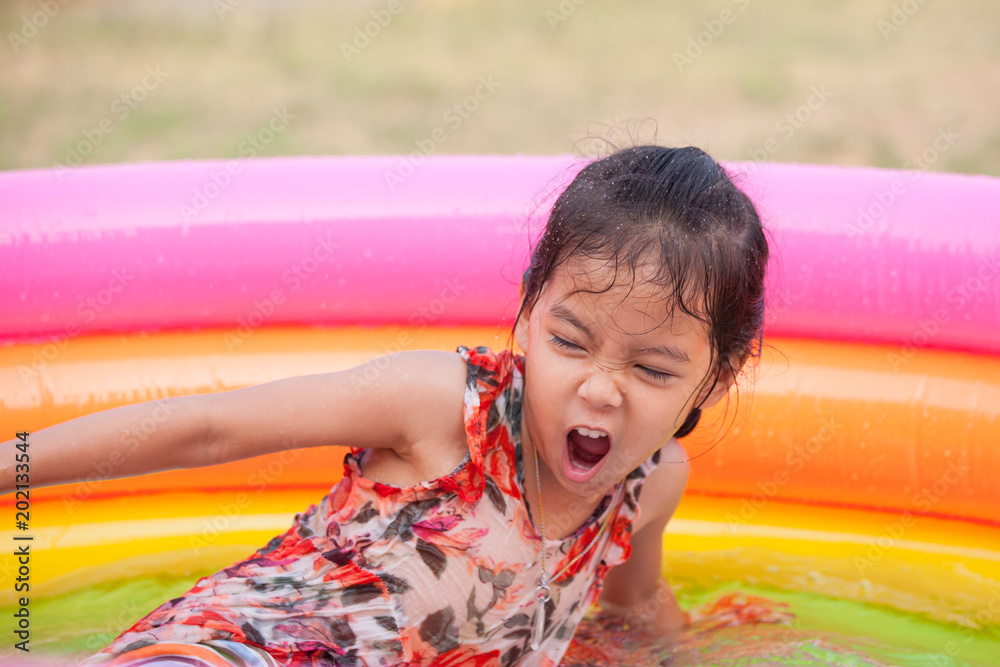 Happy asian little child girl having fun to play water in the pool in ...