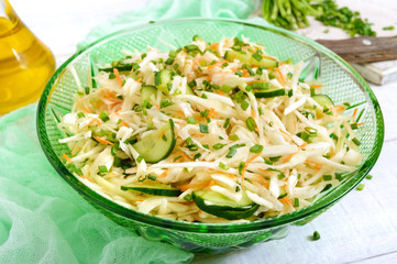 Wall Mural - Dietary salad with cabbage, cucumber, carrot, greens. Juicy spring salad from fresh vegetables on a white wooden background. Proper nutrition.