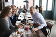 © Maskot - Smiling daughter taking selfie with parents while sitting at table in restaurant