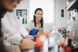 © Maskot - Confident female student looking at friends sitting in chemistry laboratory