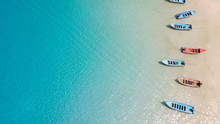 Aerial: Shoreline With Thai Fishing Boats And Long Tail Taxi Boats Parking Along The Sand Beach Of Thailand