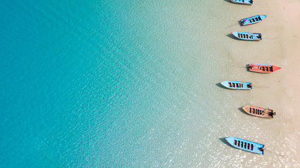 Wall Mural - Aerial: Shoreline with thai fishing boats and long tail taxi boats parking along the sand beach of Thailand