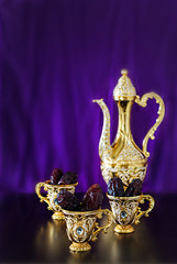 Wall Mural - Still life with dates with goldenTraditional Arabic coffee set with dallah and mini cup. Dark background. Vertical photo.