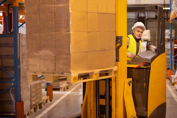 Wall Mural - Delivery system. Nice smart man driving the machine vehicle while working in the storehouse