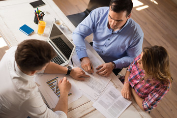 Above view of young couple signing a contract on a meeting with financial advisor.