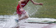 Runner splashing out of a steeplechase water pit