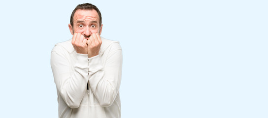 Wall Mural - Middle age man wearing sportswear terrified and nervous expressing anxiety and panic gesture, overwhelmed isolated over blue background