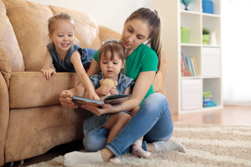 Wall Mural - pretty young mother reading a book to her kids daughters