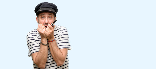 Poster - Sailor captain man smoking a tobacco pipe terrified and nervous expressing anxiety and panic gesture, overwhelmed isolated over blue background