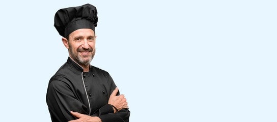 Wall Mural - Senior cook man, wearing chef hat with crossed arms confident and happy with a big natural smile laughing isolated over blue background