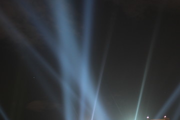 Abstract background. Searchlights shining beams of light into the black sky.