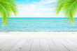 © Akura Yochi - Empty wooden table and palm leaves with party on beach blurred background in summer time.