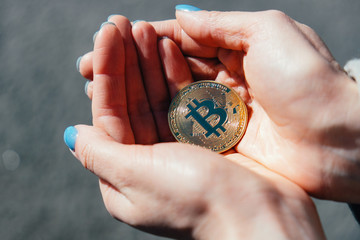 Two hands holding bitcoin. Symbol of bitcoin growing popularity