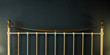 Metal bed headboard on black wall background, copy space