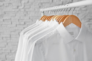 Rack with clean clothes on hangers after dry-cleaning indoors