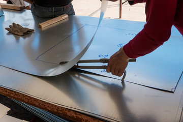 Cutting aluminum sheet with scissors of duct work for air conditioning and ventilation systems.