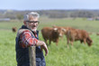 © goodluz - Farmer standing in field with cattle in background