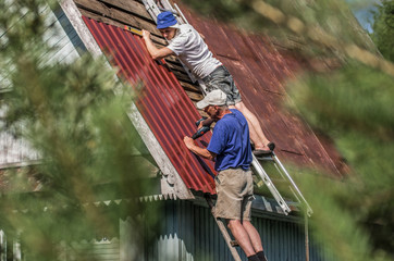 Two male workers repair the roof of a country house