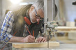 © goodluz - Woodworker in workshop designing piece of wood