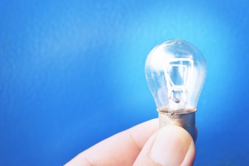 Light bulb shining , Human hand holding lamp on blue background , Spark idea and imagination
