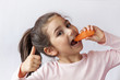 Happy little child girl eating fresh vegetables. Isolated portrait on white background. Healthy teeth.