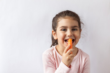 Wall Mural - Happy little child girl eating fresh vegetables. Isolated portrait on white background. Healthy teeth.