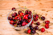 Fresh ripe cherries in glass bowl on wooden table