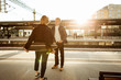 © Maskot - Happy young man talking with teenage girl while standing on railroad station platform