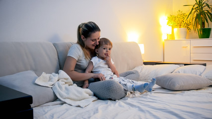 Wall Mural - Beautiful young woman sitting with her toddler son in bed at night