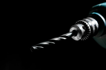 Wall Mural - Close up of drill bit on black background. Drill bit in electrical power drill with dramatically light on a dark background. shallow depth of field. Carpenter tools,home repair concept.