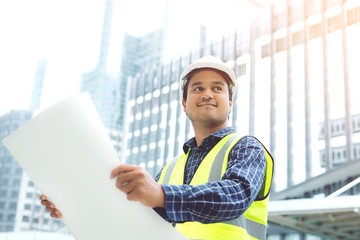 portrait of engineering asian man construction worker holding roll paper of drawing Structural plan safety white helmet and wear reflective clothing for the safety of the work operation. 