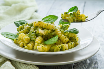 delicious pasta dish with creamy spinach sauce decorated with spinach leaves on grey wooden background