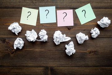 Poster - FAQ concept. Question mark on sticky notes near crumpled paper on dark wooden background top view copy space