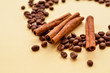 three sticks of cinnamon on a circle of coffee beans a on a yellow background