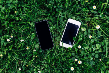 top view two phones with different screen size and lie on the green grass