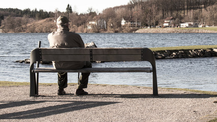 Single old man on sits on a bench