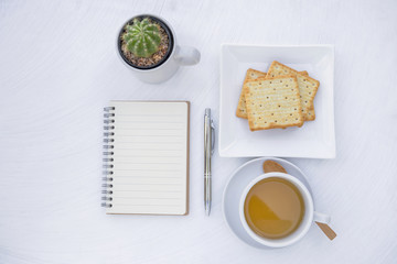 Wall Mural - Tea time, creating tme, blank notebook and silver pen with hot tea and biscuit on white table texture background