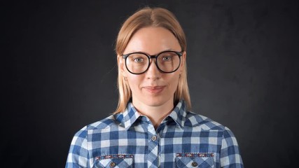Poster - portrait adult candid woman with blond hair on black background. smart girl wearing eyeglasses casual bright shirt looking at the camera