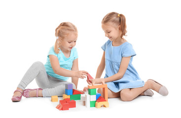 Wall Mural - Cute little girls playing with building blocks on white background