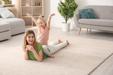 Wall Mural - Cute little girl and her mother on cozy carpet at home