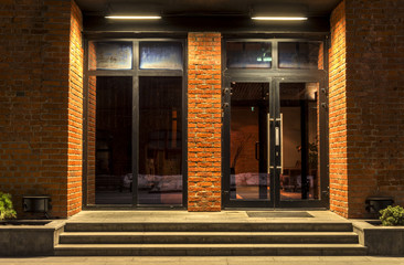 Two glass doors in a brick building in the night