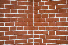 Red Brick Wall In Perspective. Angle Is In Center. Symmetric And Geometric Background Image From Red Brick.